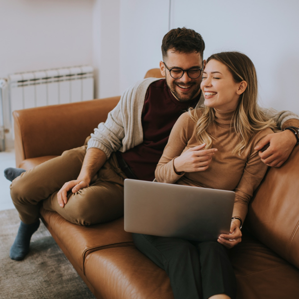 Happy couple sat on brown sofa