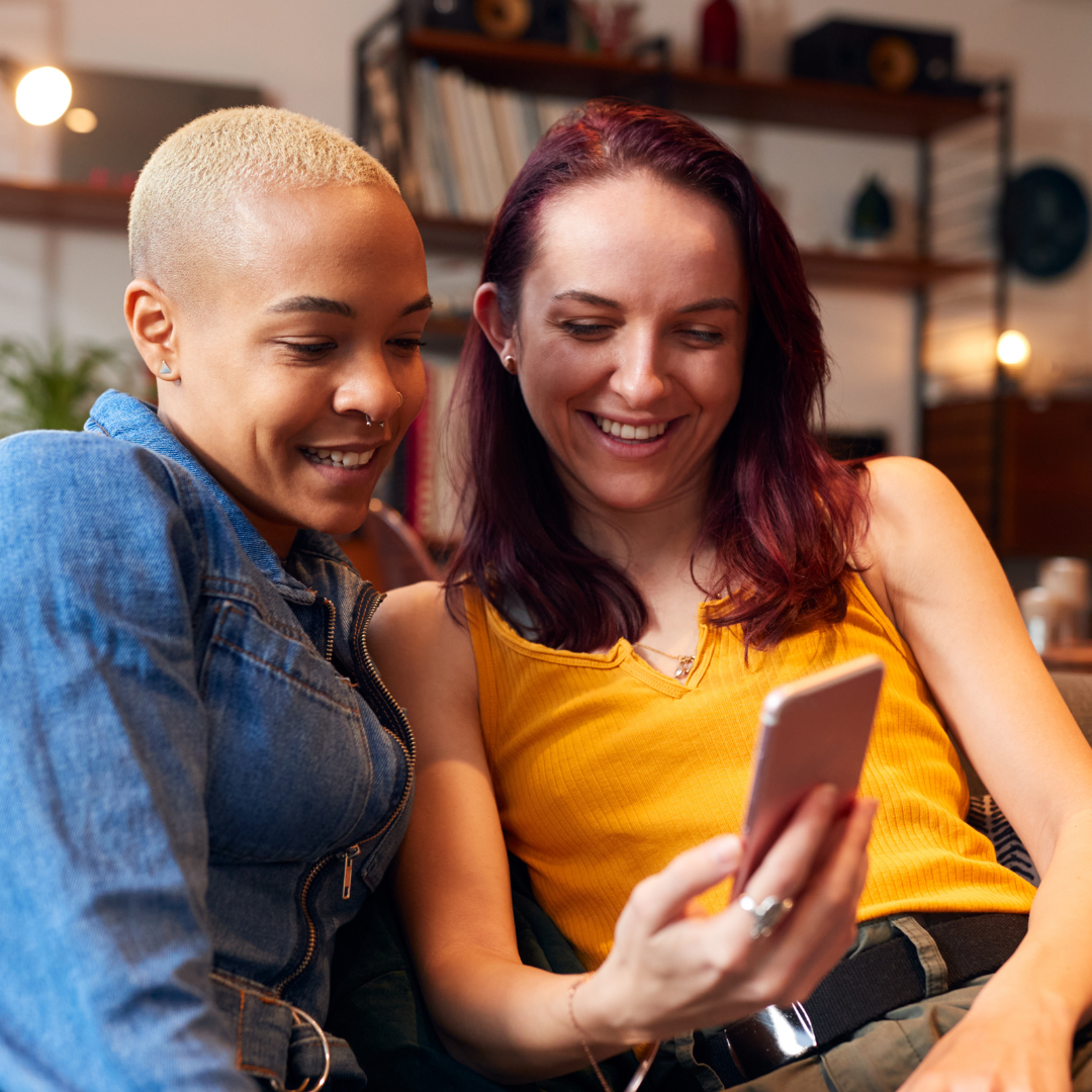 Two women smiling looking at mobile phone