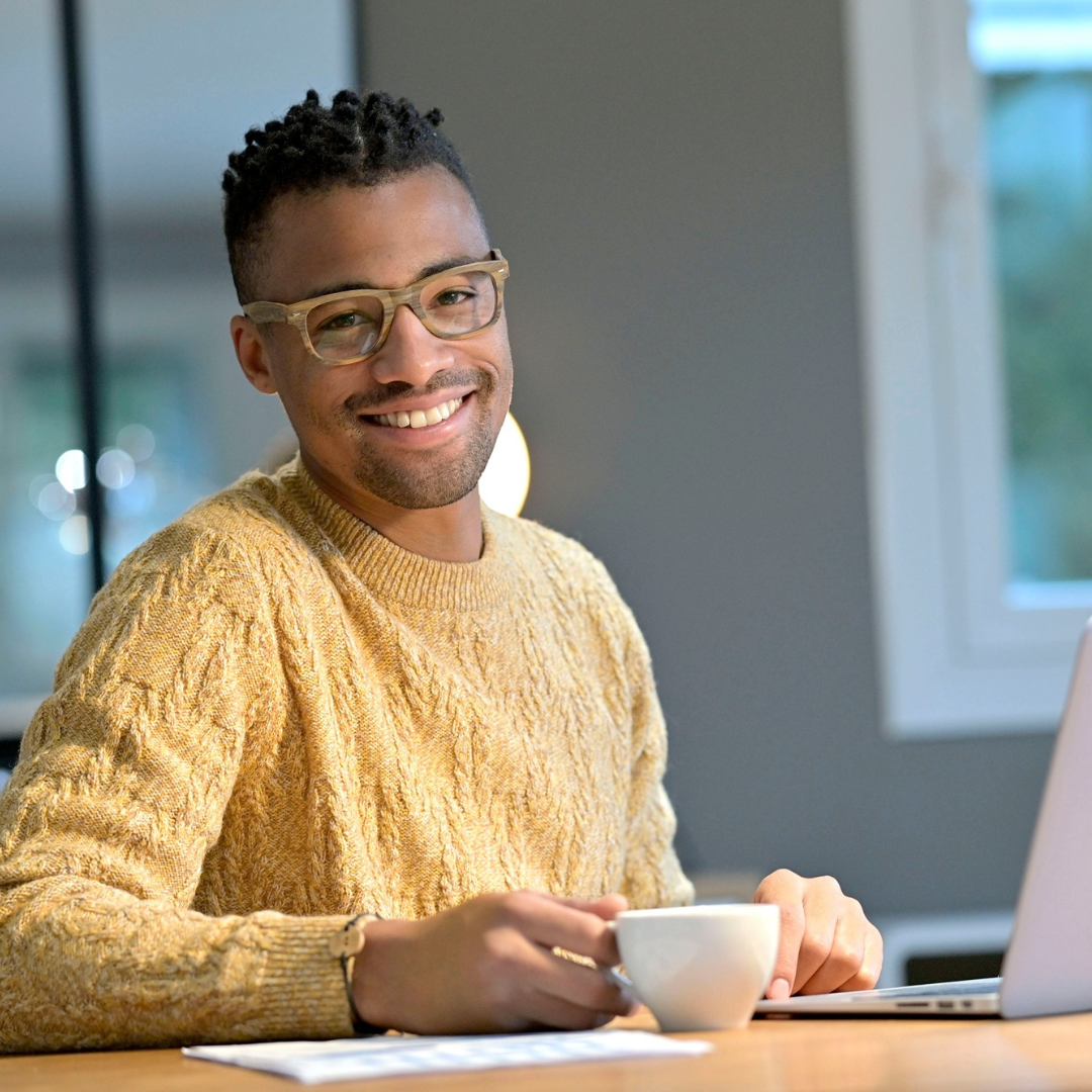 Black man with coffee sitting at laptop